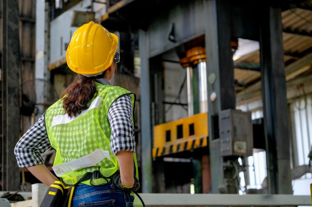 Back of factory engineer or technician worker woman stand and look in front of machine in factory