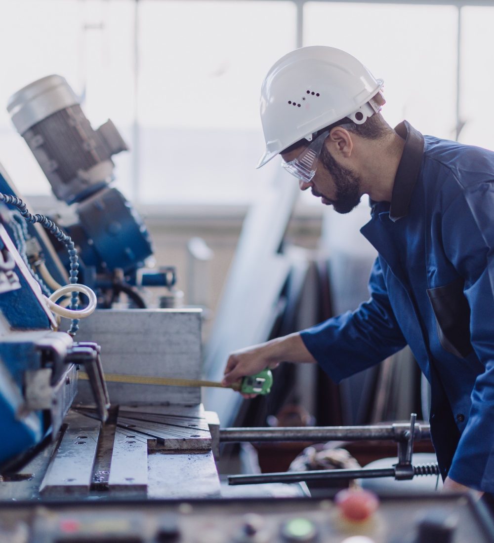Factory male worker in plant production drilling at metal machine in industrial factory.